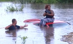 Người phụ nữ ngồi trên nóc xe giữa dòng nước ngập