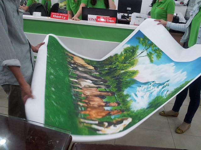 In tranh canvas tại In Kỹ Thuật Số - khách hàng kiểm tra thành phẩm in tranh canvas khi nhận hàng