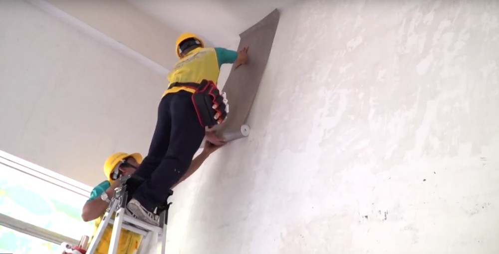 Cầm cả cuộn vải đưa lên bề mặt tường và xả từ từ cuộn vải dán tường